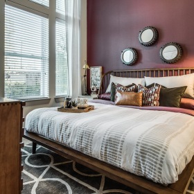 Model apartment bedroom furnished, carpeted bedroom with large windows